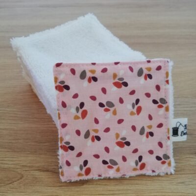 photo d'un lot de 10 petites lingettes, avec une face en éponge douce blanche et l'autre face rose pastel avec des pétales gris, bordeaux, blancs, jaunes et oranges