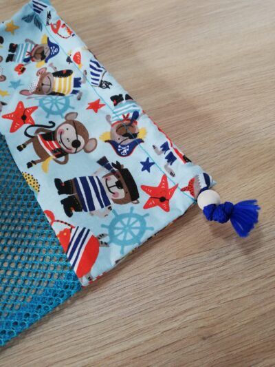 photo zoom sur le système de fermeture (cordon et perle en bois) du filet de lavage appartenant au kit lingettes bleu ciel motifs animaux pirates