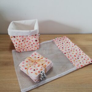 photo d'un kit lingettes composé d'un lot de 10 lingettes, d'un filet de lavage et d'une panière, confectionné avec le même coton rose orangé motifs petits cœurs