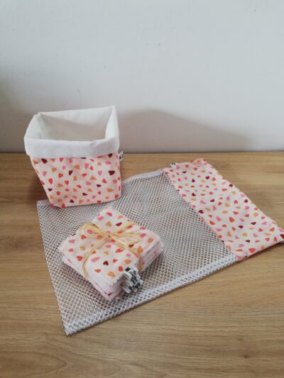 photo d'un kit lingettes composé d'un lot de 10 lingettes, d'un filet de lavage et d'une panière, confectionné avec le même coton rose orangé motifs petits cœurs