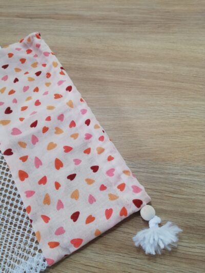 photo zoom sur le système de fermeture (cordon et perle en bois) du filet de lavage appartenant au kit lingettes rose orangé motifs petits cœurs