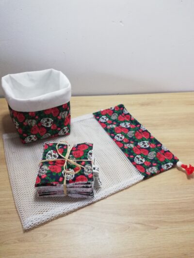 photo d'un kit lingettes composé d'un lot de 10 lingettes, d'un filet de lavage et d'une panière, confectionné avec le même coton aux motifs roses et crânes blanc, noir et rouge